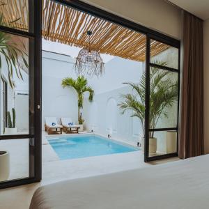 einen Pool in einer Villa mit einem großen Fenster in der Unterkunft The Serendipity Palms Villa by Hombali in Canggu