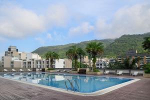 a swimming pool with palm trees and buildings at Evergreen Resort Hotel - Jiaosi in Jiaoxi