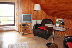 ein Wohnzimmer mit Tisch und Fernseher in der Unterkunft Ferienhof Serck - Galeriewohnung in Fehmarn