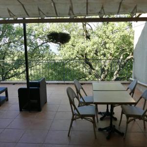 een patio met een tafel en stoelen en een televisie bij Le Bosquet in Aiguines