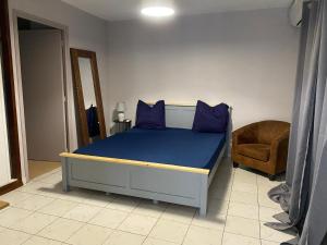een bed met blauwe kussens en een stoel in een kamer bij Appartement T2 Kaweni in Mamoudzou