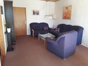 ein Wohnzimmer mit zwei blauen Sofas und einem Tisch in der Unterkunft Ferienhof Serck - Große Wohnung in Fehmarn