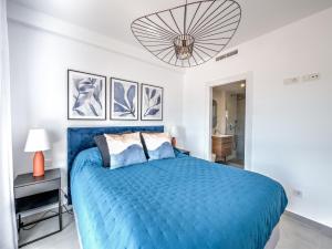 um quarto com uma cama azul e um lustre em New Luxurious house with rooftop terrace and pool em Nerja