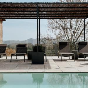- un groupe de chaises assises à côté de la piscine dans l'établissement Hotel Palau Macelli, à Castelló d'Empúries