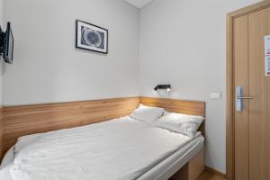 a bed with white sheets and a wooden headboard at Stay Express Hotel in Vilnius