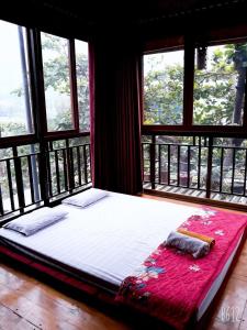 een groot bed in een kamer met ramen bij Nhà nghỉ 28 - Homestay Biên Thùy, Bản Lác, Mai Châu, Hòa Bình in Mai Chau