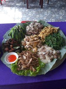 Nhà nghỉ 28 - Homestay Biên Thùy, Bản Lác, Mai Châu, Hòa Bình في ماي تشاو: طبق من الطعام على طاولة أرجوانية