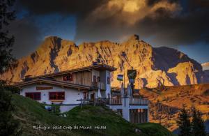 une maison sur une colline en face d'une montagne dans l'établissement Rifugio Crëp de Munt, à Corvara in Badia