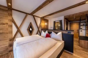 duże białe łóżko w pokoju z drewnianymi ścianami w obiekcie Rifugio Crëp de Munt w mieście Corvara