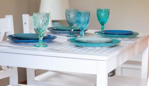 a white table with blue plates and glasses on it at Casa de Buenas in Sarbinowo