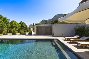 a swimming pool with two lounge chairs and an umbrella at Villa Bizzarria in Castellammare del Golfo