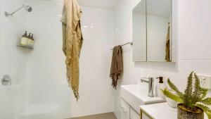 a white bathroom with a sink and a mirror at Mullum Haven 3 - Central & Stylish Townhouse in Mullumbimby