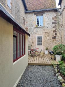 une terrasse en bois avec deux chaises et une table en face d'un bâtiment dans l'établissement Le Coeur de Fresnay, à Fresnay-sur-Sarthe