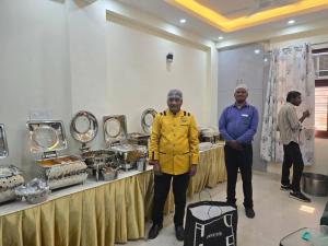 two men standing in front of a table with food at Homlee-Vasundhara 5BHK with Terrace(For Function) in Ghaziabad