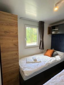 a small bedroom with a bed with a window at Mobile Home - Sea La Vie in Biograd na Moru