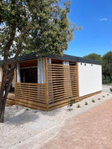 a wooden cabin with a white door and a tree at Mobile Home - Sea La Vie in Biograd na Moru
