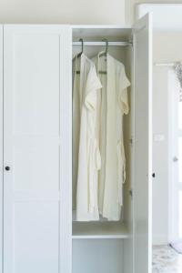 a closet with white clothes hanging in it at KW by Trava All Inclusive Boutique Hotel in Chiang Mai