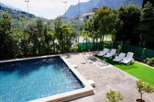 a swimming pool with lounge chairs next to a yard at Hotel Diana in Riva del Garda