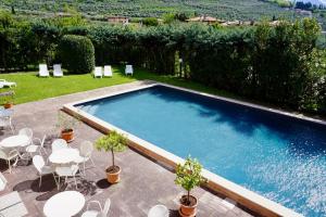a swimming pool with white tables and chairs at Hotel Diana in Riva del Garda