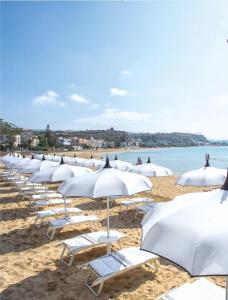 a row of white umbrellas on a beach at Appartamento Punta Grande - Scala dei Turchi in Realmonte