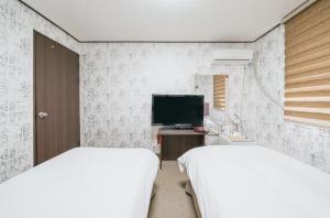 a bedroom with two beds and a tv in it at Manhattan Hotel in Jeju