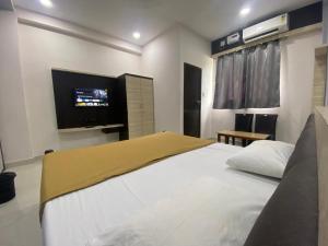 Schlafzimmer mit einem Bett und einem Flachbild-TV in der Unterkunft Dhanya Lodge in Padubidri