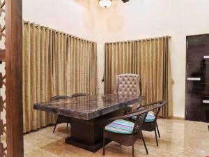 Shore Beats Villa في مومباي: طاولة وكراسي في غرفة مع ستائر