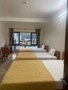 - une rangée de trois lits dans une chambre d'hôtel dans l'établissement Blue Rose Hotel, à Hạ Long