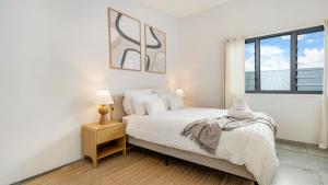 a white bedroom with a bed and a window at Mullum Haven 3 - Central & Stylish Townhouse in Mullumbimby