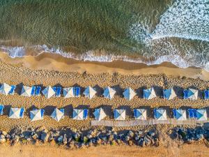 an overhead view of a beach with blue and white umbrellas at Arina Beach Resort in Kokkini Khanion