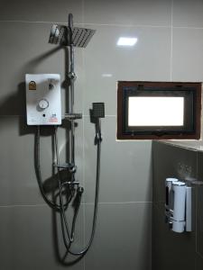 een douche in de badkamer met een spiegel bij บ้านอยู่ดีโฮมสเตย์ 