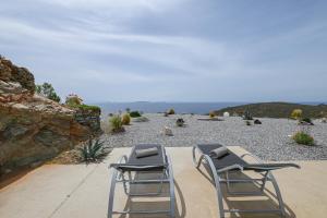 two chairs sitting on a patio looking out at the ocean at Dream Cave Villa Tinos in Tinos Town