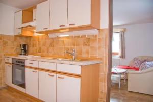 a kitchen with white cabinets and a sink at Ferienwohnung Grüsser-kagerhuber in Schönau am Königssee +7 photos