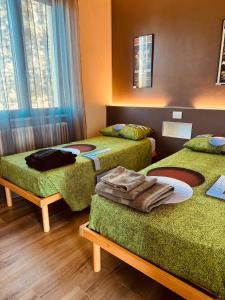 a room with three beds with green blankets and a window at Casetta Fausta immersa nel Golf Margara. in Fubine