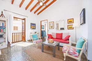 a living room with a red couch and a table at Poppy's Beach House in Colònia De Sant Jordi