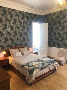 Javerlhac-et-la-Chapelle-Saint-Robertにあるchâteau de Puymogerの緑の花の壁紙を用いたベッドルーム1室