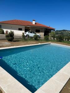 a blue swimming pool in front of a house at Quinta da Travessa in Cinfães