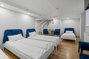 two beds in a room with blue chairs and a table at Stay Express in Vilnius