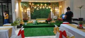 a room with a green carpet and a table with people at Balai Subik Hotel in Olongapo