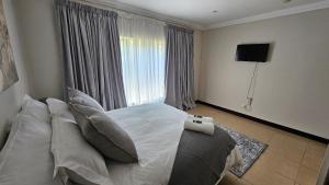 una camera da letto con letto, cuscini e finestra di Grobler's Haven a Pretoria