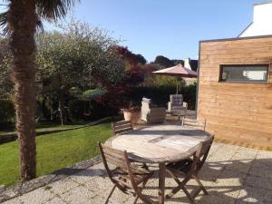 a wooden table with chairs and an umbrella in a yard at Charmante maison avec jardin à Guidel, proche nature in Guidel
