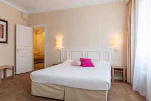 ルマンにあるThe Originals City, Hôtel Chantecler, Le Mansのベッドルーム1室(白い大型ベッド1台、ピンクの枕2つ付)