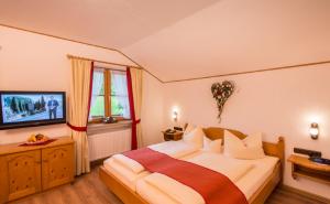 a bedroom with a large bed and a television at Hotel Alpspitz B&B in Grainau