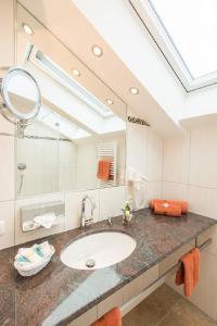 ein Badezimmer mit einem Waschbecken und einem großen Spiegel in der Unterkunft Hotel Alpspitz B&B in Grainau