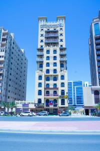 a tall white building with cars parked in front of it at Palette Royal Reflections Hotel and Spa Dubai in Dubai