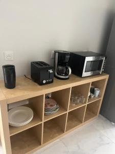 a microwave and a coffee maker on a wooden shelf at Logement entier limay in Limay