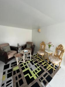 uma sala de estar com cadeiras e mesas num tapete em Logement entier limay em Limay