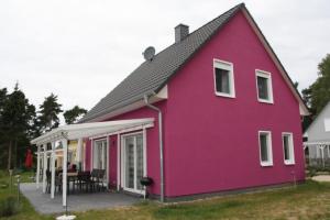 ein rotes und violettes Haus mit einer Terrasse in der Unterkunft K 95 - Modernes Ferienhaus mit Kamin in Roebel an der Mueritz in Marienfelde