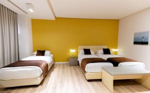 two beds in a hotel room with yellow walls at Best Western Premier Ark Hotel in Tirana