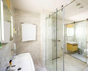 a bathroom with a glass shower and a sink at Best Western Premier Ark Hotel in Tirana